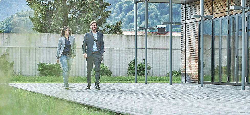 Frau und Mann auf Terrasse vor Haus im Grünen